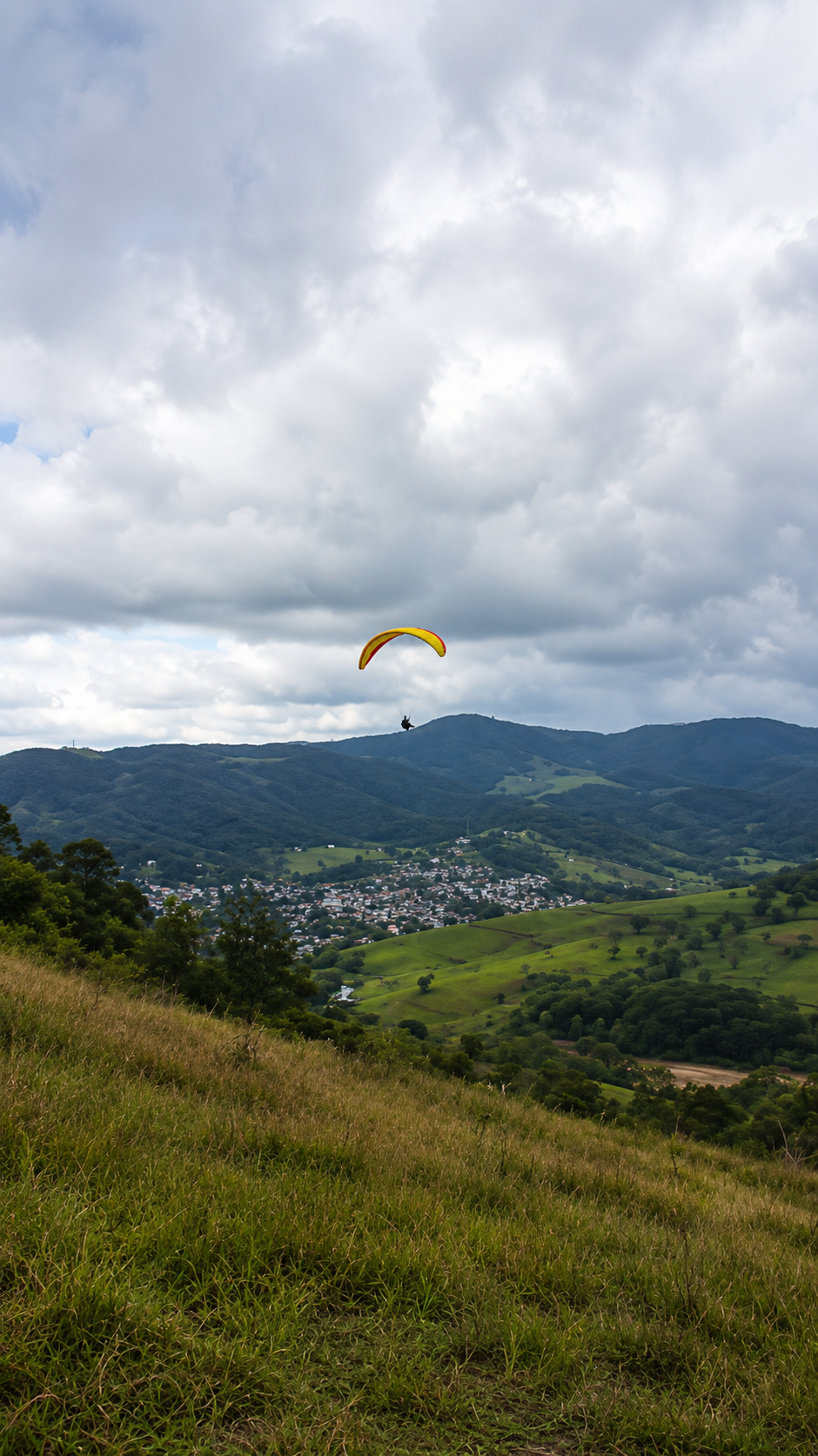 Parapente sobrevoando o vale e as montanhas de Juiz de Fora